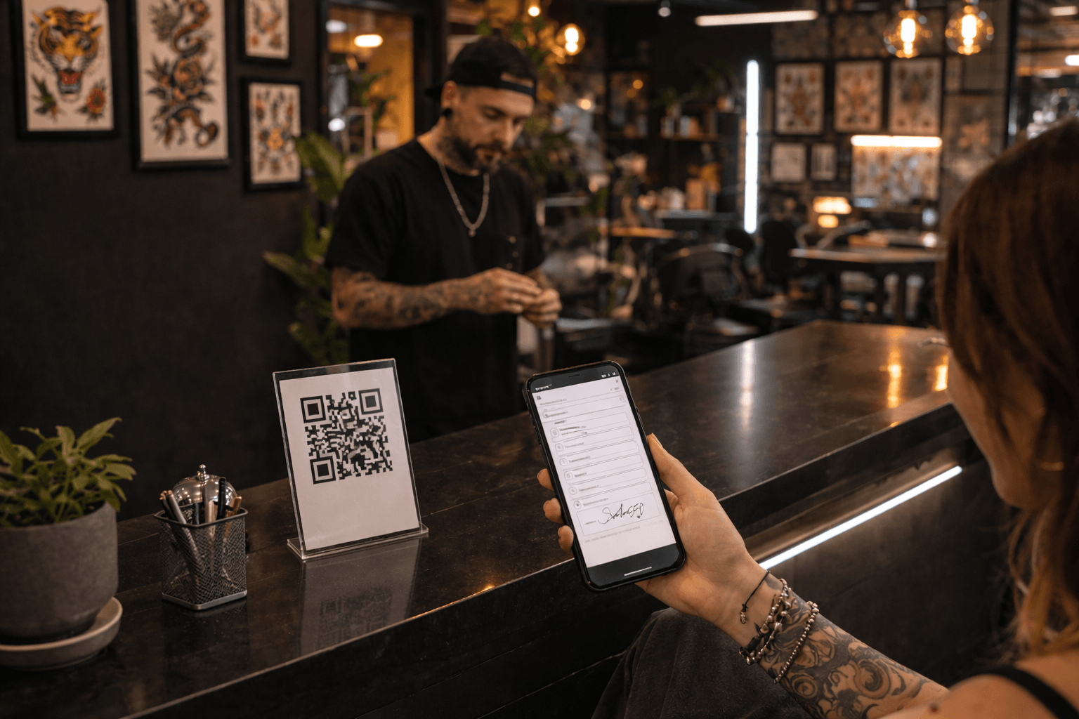Client signing a digital tattoo consent form on their phone via QR code at a tattoo studio counter